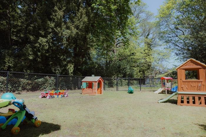 Omheinde buitenspeeltuin met speelhuisjes en glijbaan