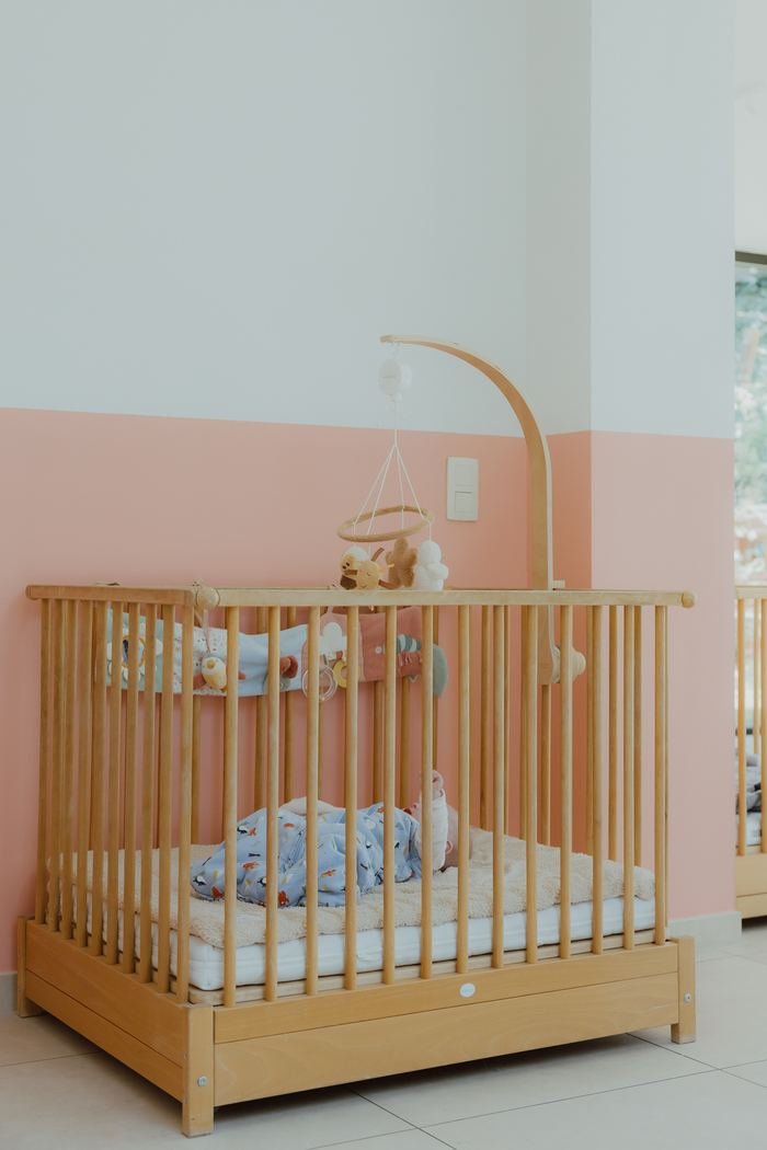 Baby slaapt rustig in de wieg met een mobiel erboven